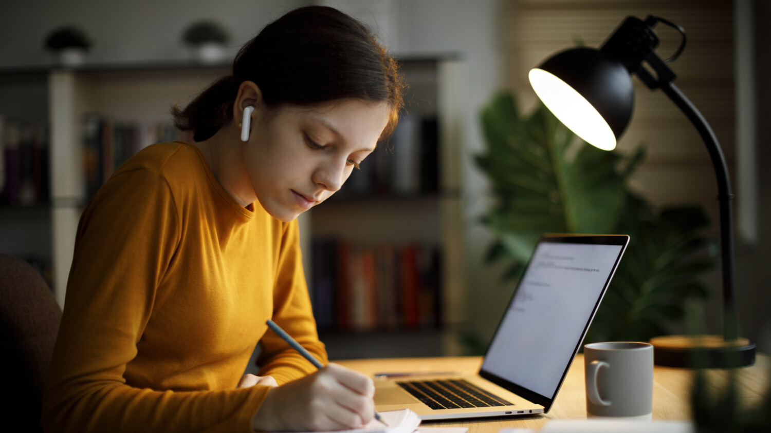 Girl with headphones in front of a laptop.