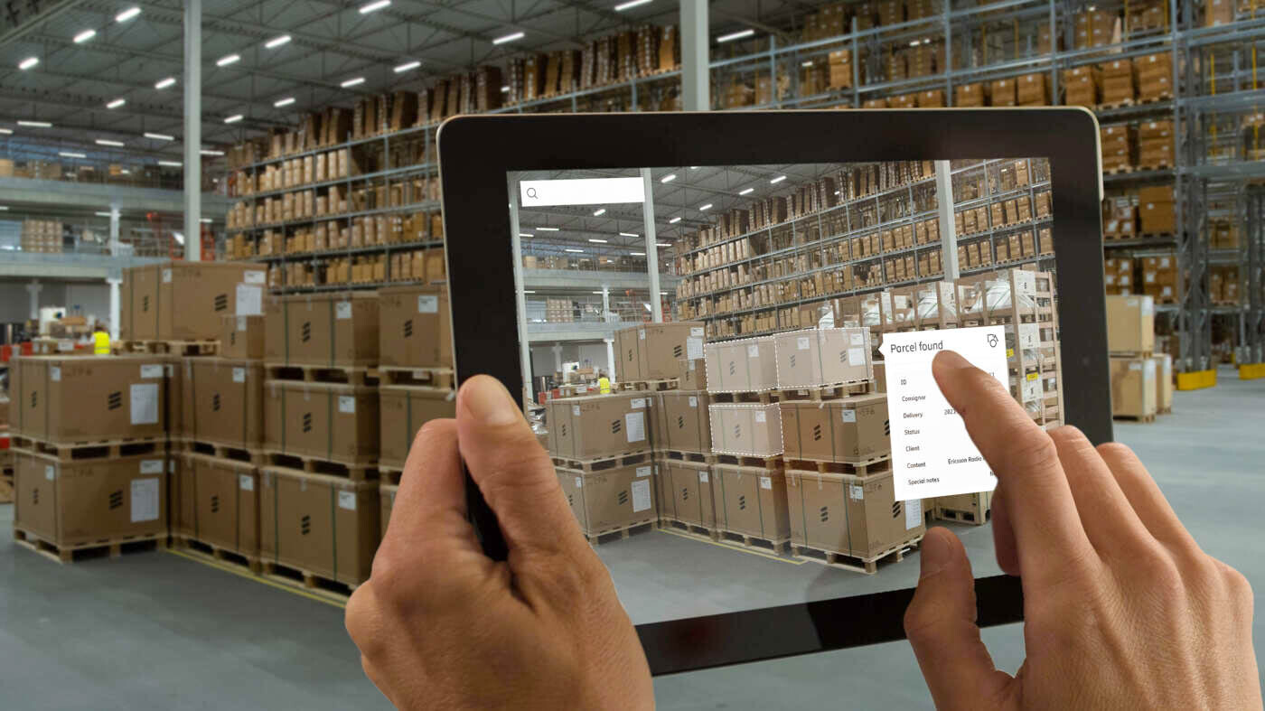 Hands holding tablet, asset tracking in warehouse using AR app.