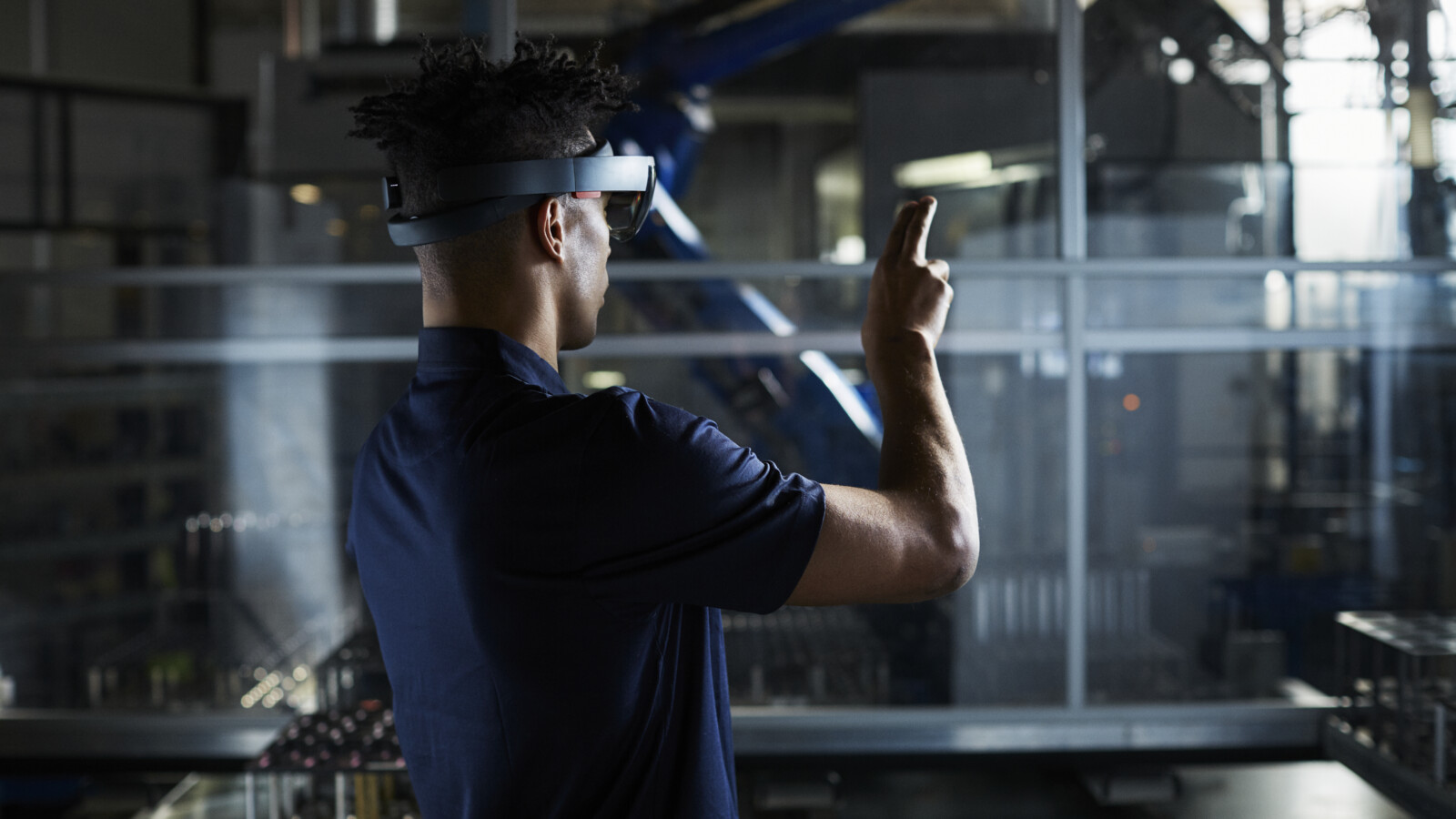 Man in robot factory using AR glasses.