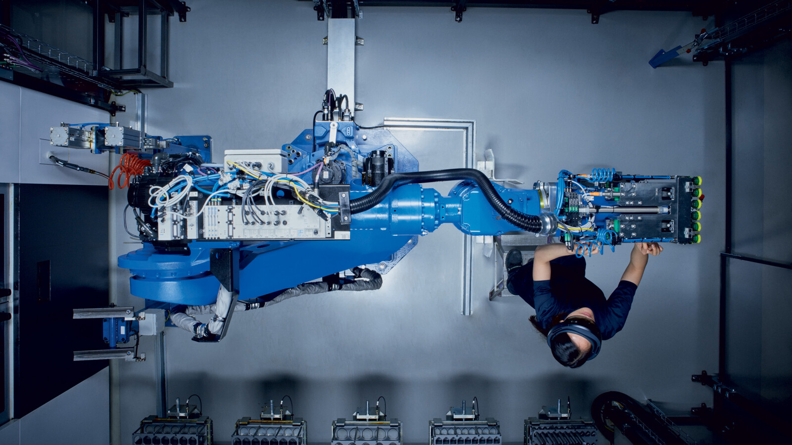 Engineer in factory with robotic arm.