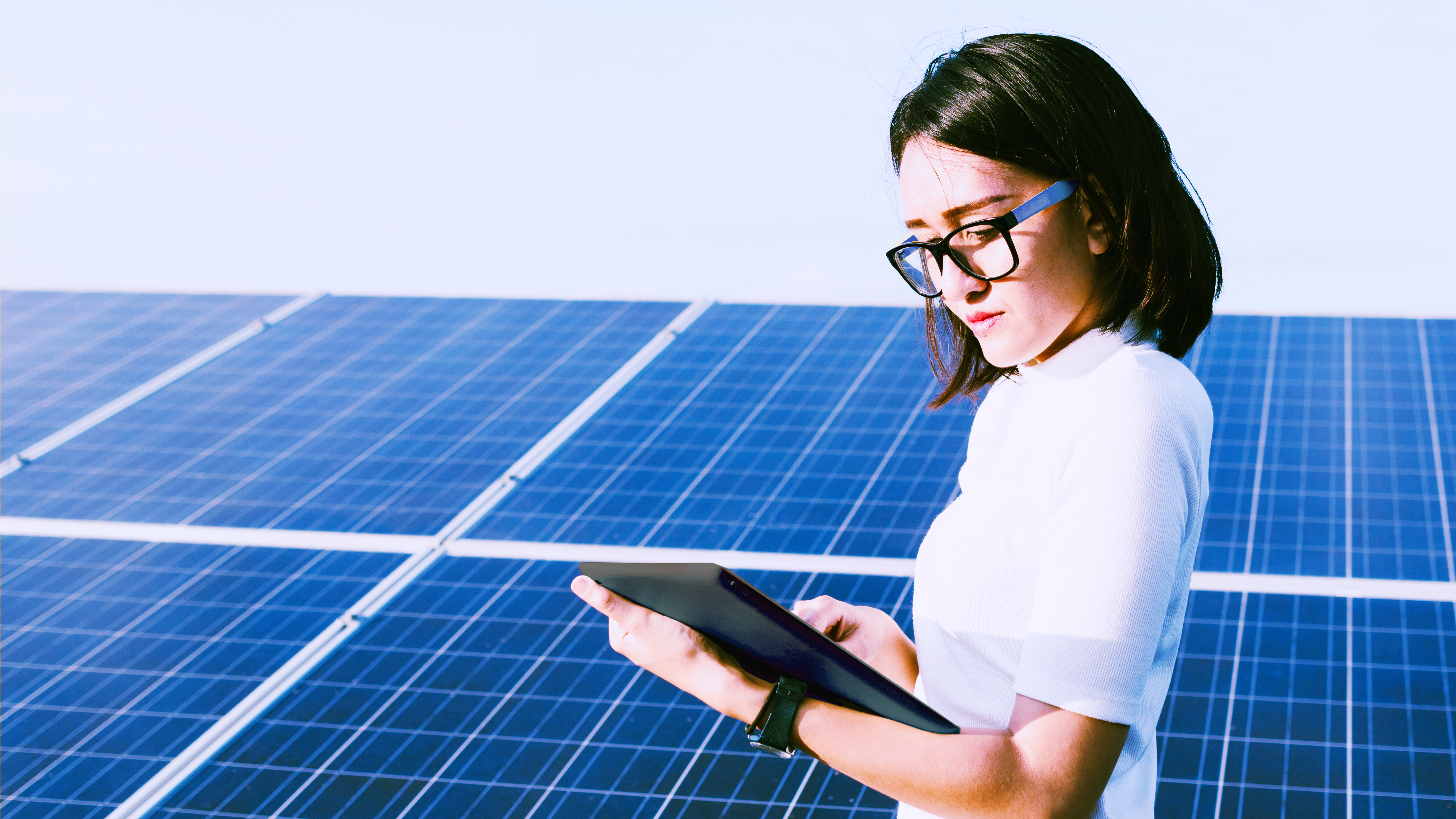 Engineer working on checking status using a device in front of solar panels.