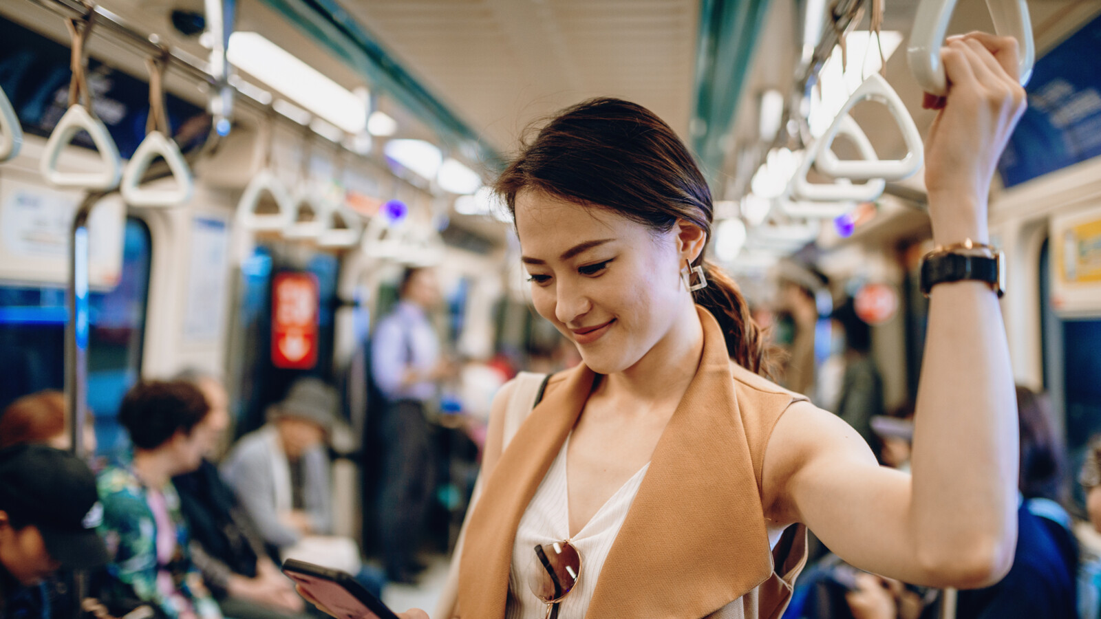 Woman standing on the subway looking at mobile device