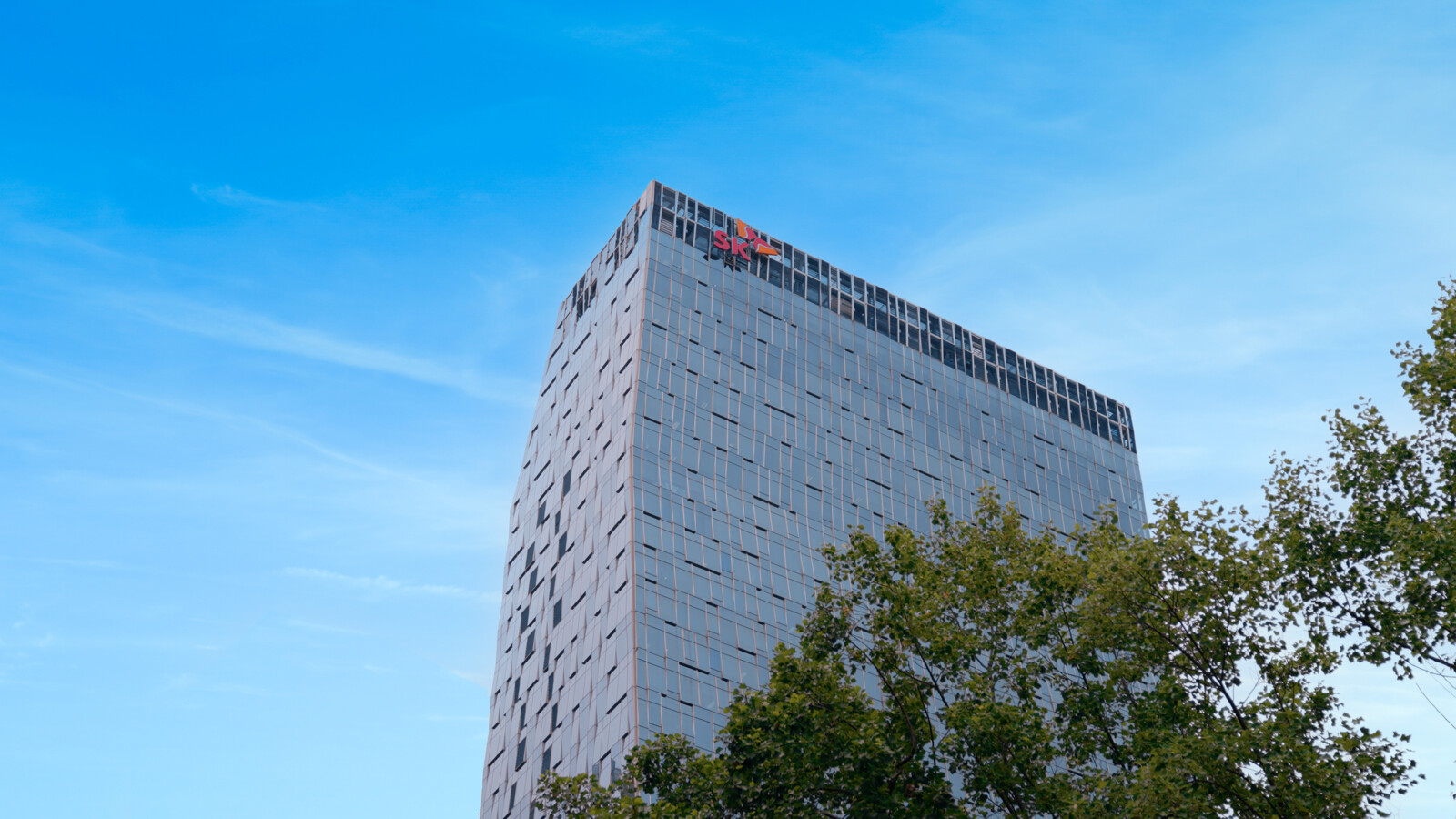 Tall building with windows and trees under blue sky.