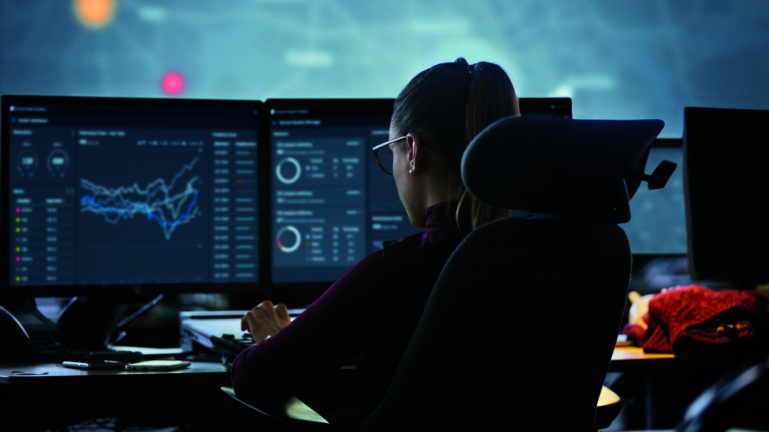 Woman in front of screens with interfaces visible.