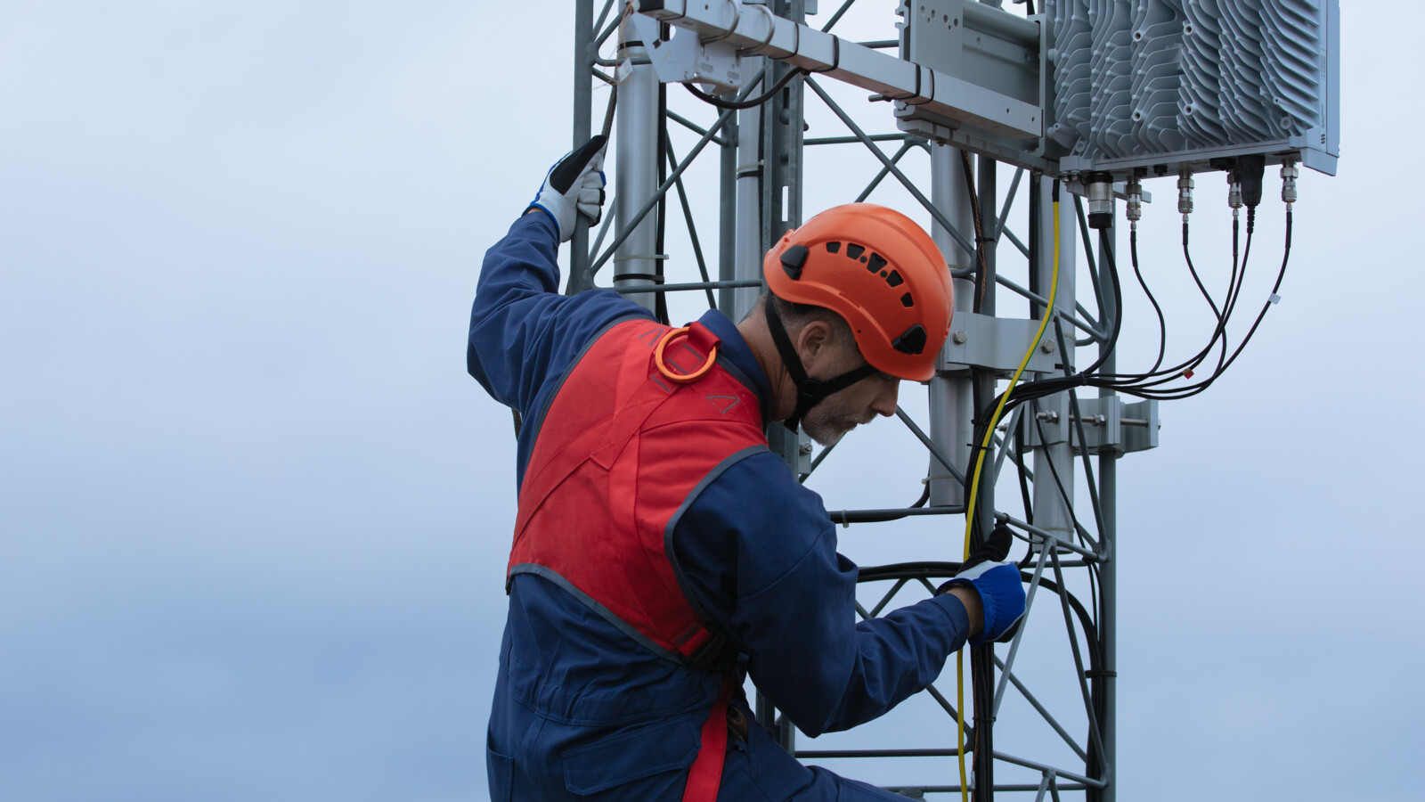 A man climbing a tower, connecting network cables on site