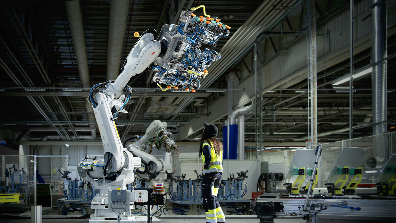Woman standing in front of a big factory robot.